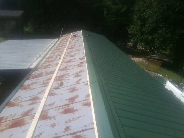 Old rusted panels beside newly installed green metal roofing — Wind Damage Roof Repair by Roofing Brothers in Charlotte Court House