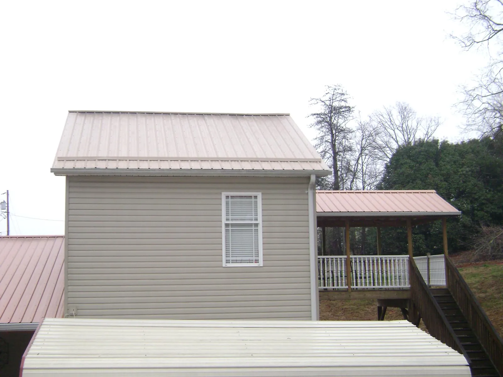 Tan metal roofs on a two story addition and attached porch, from a Roof Replacement job in Charlotte Court House